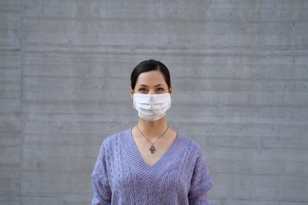 a woman in a purple sweater wearing a face mask